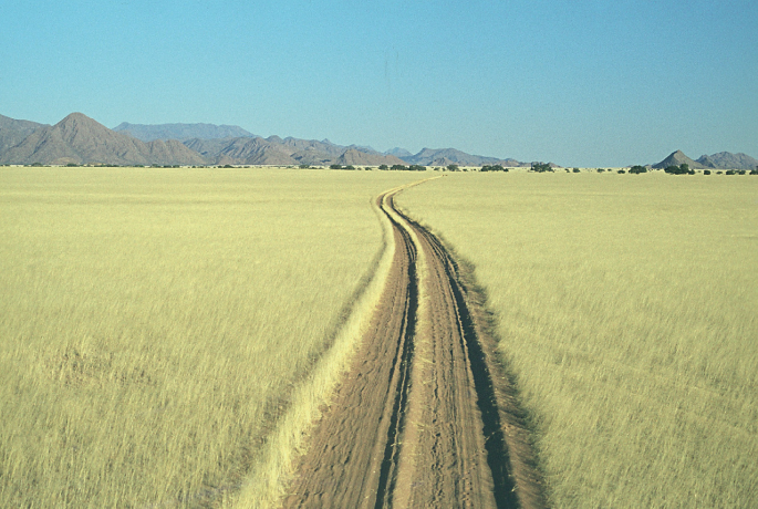 A photograph of a mountain view with dry grasses, houses, and roads.