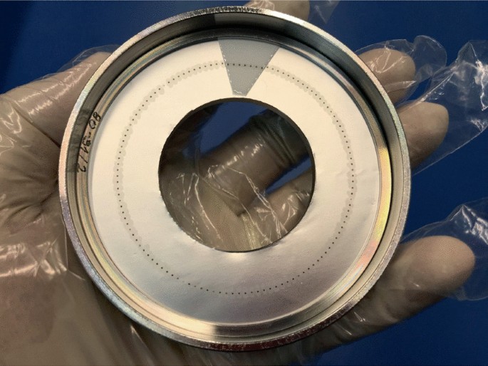 A photograph of a Petri dish-like plate that has a hole in the center.