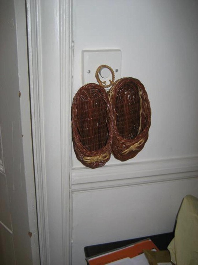 A close-up photo exhibits a pair of knitted slippers hanging on the wall.