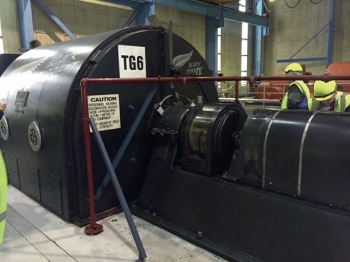 A photograph of a Black Current Generator. It is a horizontal structure with men working beside it. It has, T G 6, written on it.