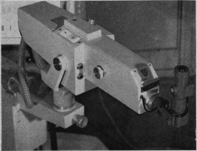 A close-up of a ruby laser photocoagulator. It has an eyepiece, a height-adjusting knob at the base, and connecting wires.