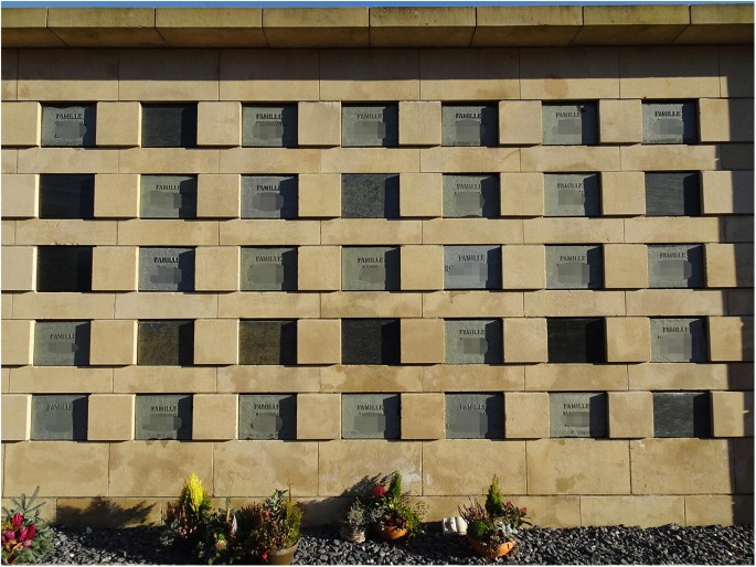 A photograph of columbarium at Notre Dame cemetery. It is a structure with square compartments for urns with names.