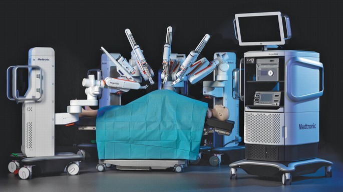 A photograph of a robotic-assisted surgery system. It consists of a Hugo vision cart, modular robotic arms, and the surgeon control console.
