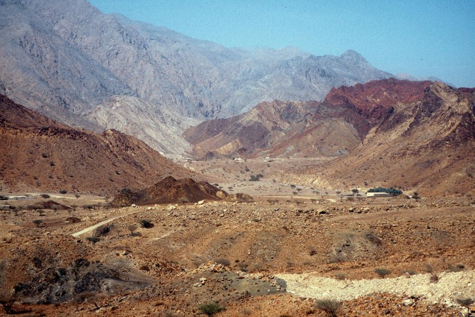 The photograph of a mountainous landscape with rocky terrain and steep cliffs. The vegetation is sparse and consists of small shrubs and cacti. There are no buildings or roads visible in the image.
