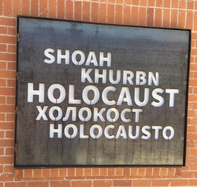 A close-up photograph of a sign with the word holocaust in different foreign languages including one in English.