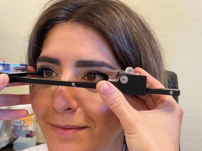 A photograph illustrates the measuring the A G P of a female patient using the instrument, namely an exophthalmometer. The instrument is placed on the face of the patient in front of the eyes.