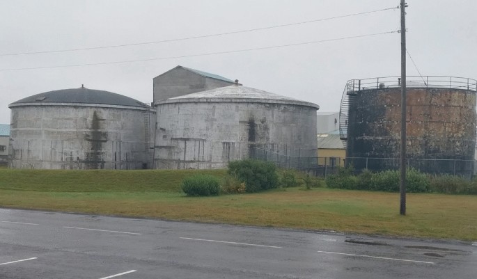 A photo of two dome-shaped silos by the side of a road. Another tarnished silo is present next to these silos.