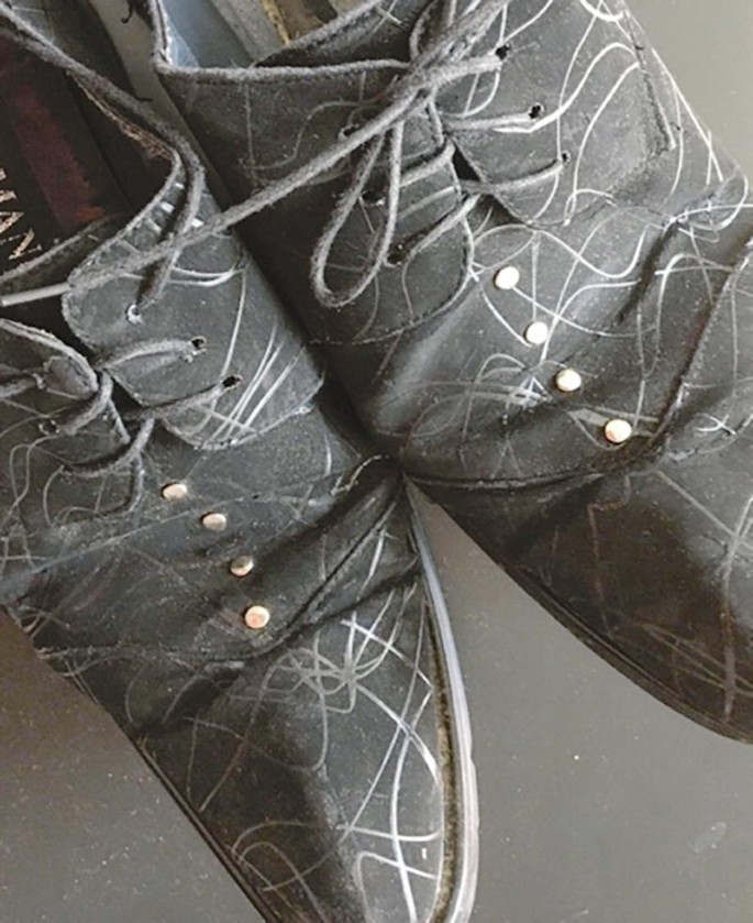 A photograph of dark suede shoes with pointed tips, thin laces, and small adorned buttons.