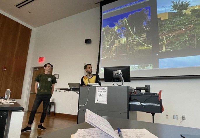 A photograph of Josh Morin and Aaron Lewis of Temperance Alley presenting photos on a projector.
