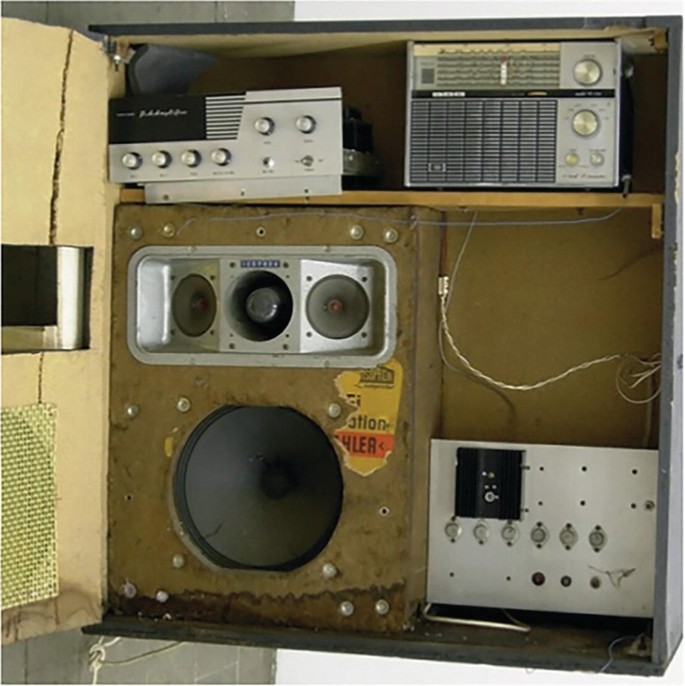 A photograph of audio technology devices arranged in a cabinet.