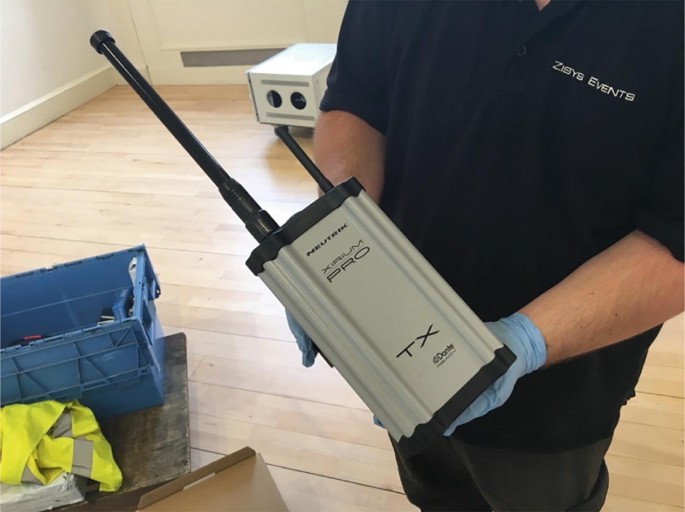 A photograph of the Xirium Pro transmitter held in the hands of Zisys Events person.