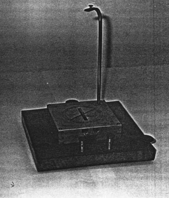 A historical photo of a rectangular shaped, Galvanometer device with a vertical pole.