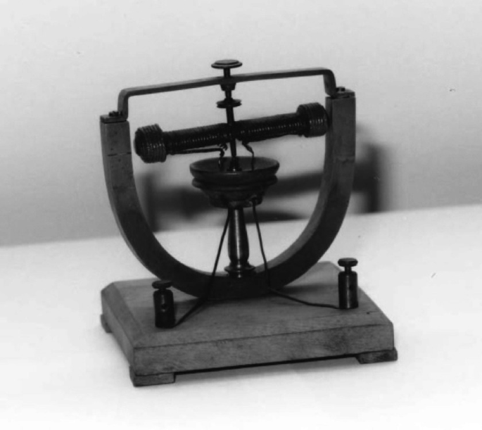A historical photo of a U shaped electric motor displayed on a square shaped platform.