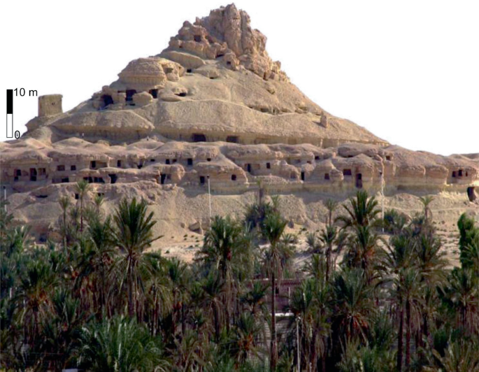 A photograph of mosses-rich tufa at Kurkur Oasis in southern Egypt. It is an isolated, conical-shaped hill formed by differential weathering. The hill consists of Middle Miocene siliciclastic-carbonate deposits formed in a shallow marine environment.