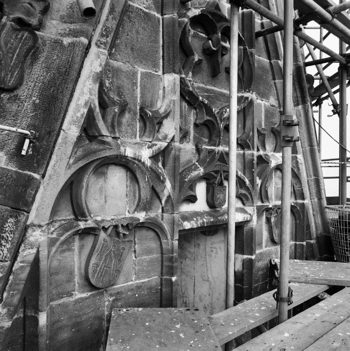 The interior of a cathedral with scaffolding and various coats of arms on the walls and ceiling.