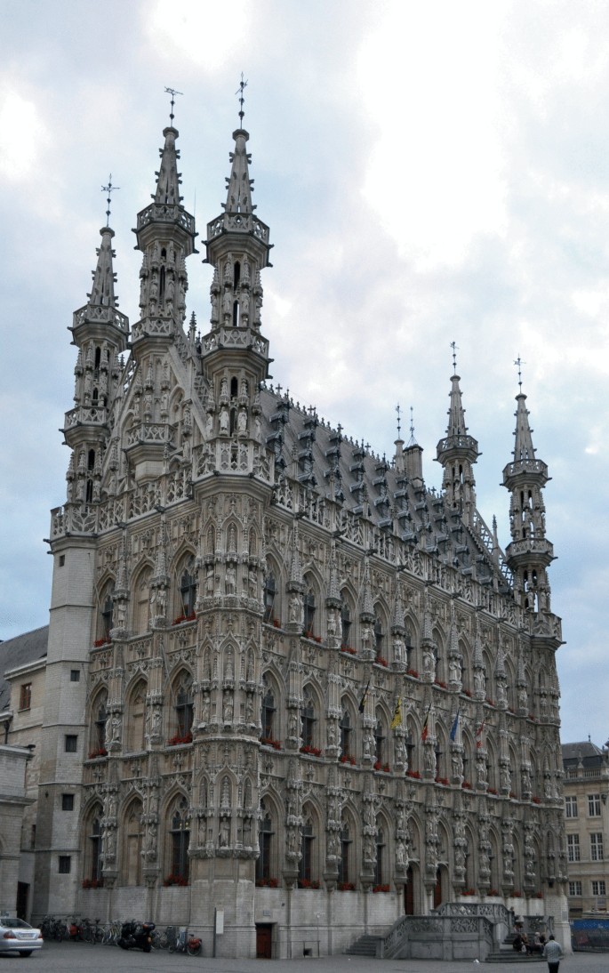A photo of Leuven's town hall presents a large building with many windows, towers, and highly decorated facades.