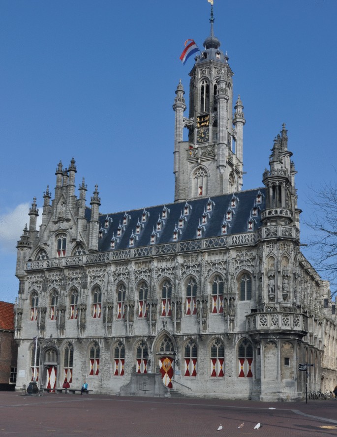 A photo of a large building located in Middelburg, Netherlands, with many arched windows, featuring ornate gables and towers.