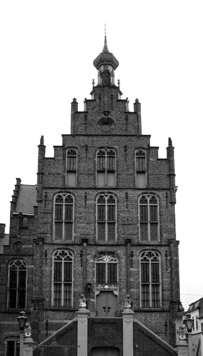 A black and white photo of a historic building with a tall tower, arched windows, and ornate details.