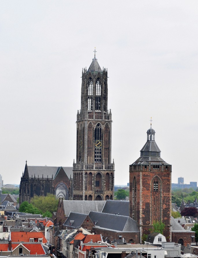 A photo of the Dom tower located in Utrecht, Netherlands. It is a large building with a clock tower and a tall spire.