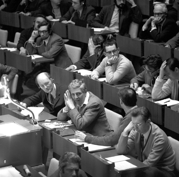 A photograph of Herwig attending a lecture. He is seated in an auditorium with many others.
