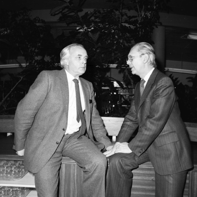 A photograph of Herwig and Josef Rembser discussing in an open environment.