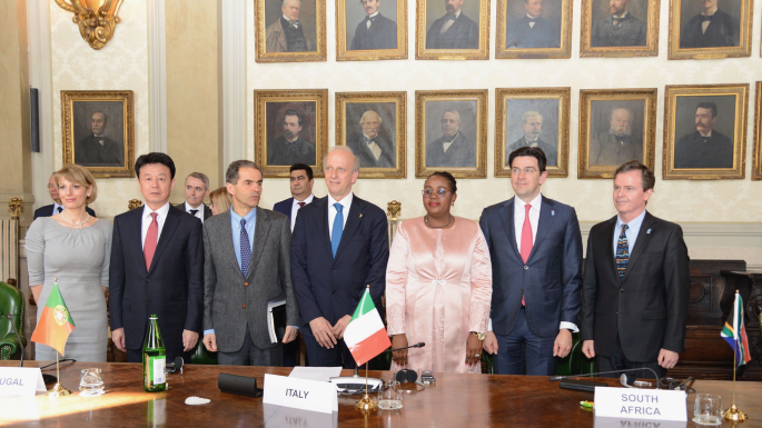 A photograph of a group of people at Signatories to the SKA Convention in Rome. There are several photo frames placed on the wall behind them.