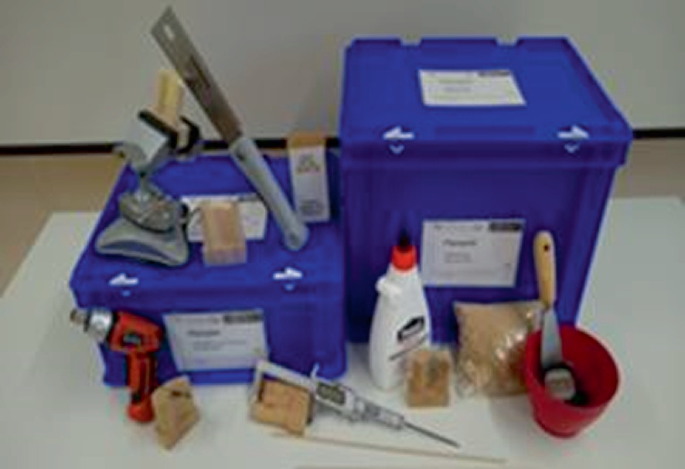 A photograph of the worksheet for the business game, featuring two plastic boxes, a screwdriver, a drill machine, and other tools used for repairing and troubleshooting.