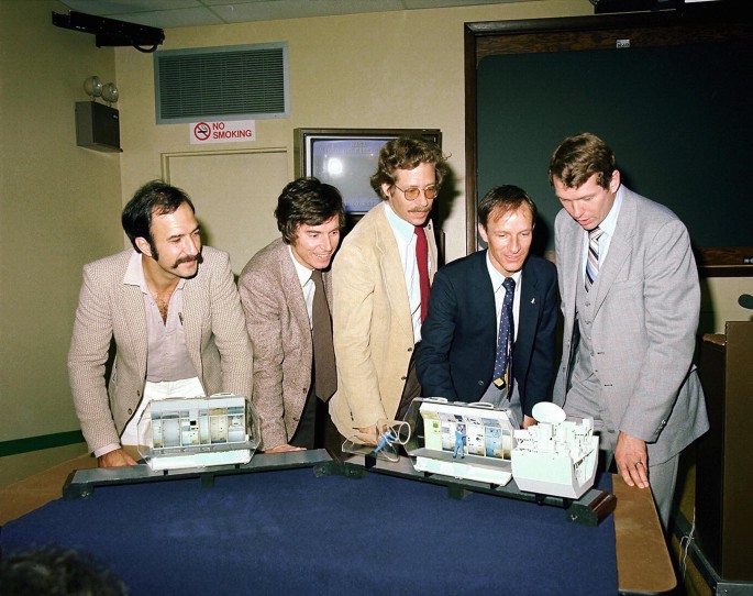 A photograph of Wubbo Ockels, Ulf Merbold, Mike Lampton, Claude Nicollier and Byron Lichtenber, examining the two models placed on the table, during Spacelab-1 training.