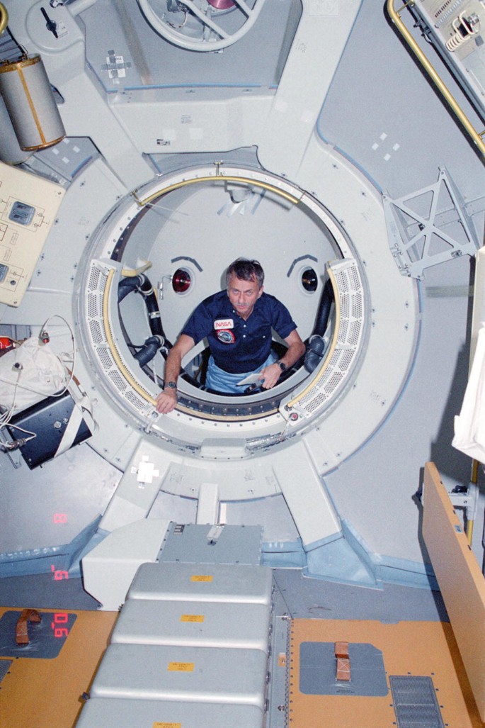 A photograph Owen Garriott coming out from the tunnel of the Spacelab-1 module.