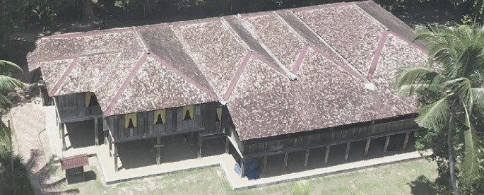 A photo from the top view of the house. The roof tiles have a mosaic-like pattern. The house has various classic window designs with curtains.