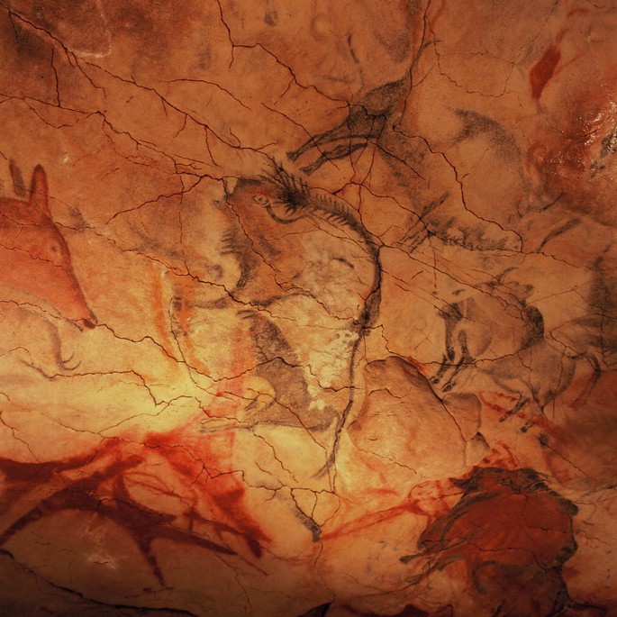 A photograph of the Altamira cave painting on the ceiling depicts various animals, including a large bison and a horse, on a cracked and textured stone surface.