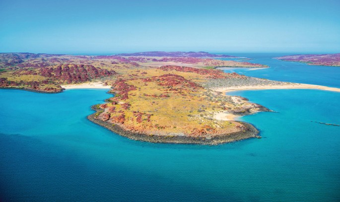 A photo of aerial view of Murujuga. Murujuga has rocky landforms, rugged coastline, and several peninsular projections.