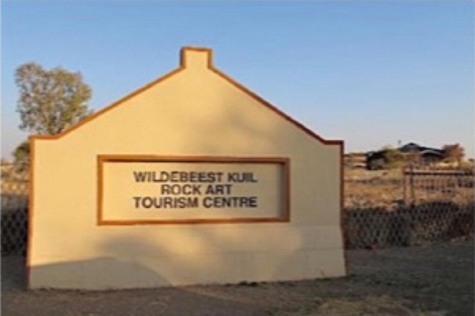 A large concrete block with a text inscribed as, Wildebeest Kuil Rock Art Tourism Center.