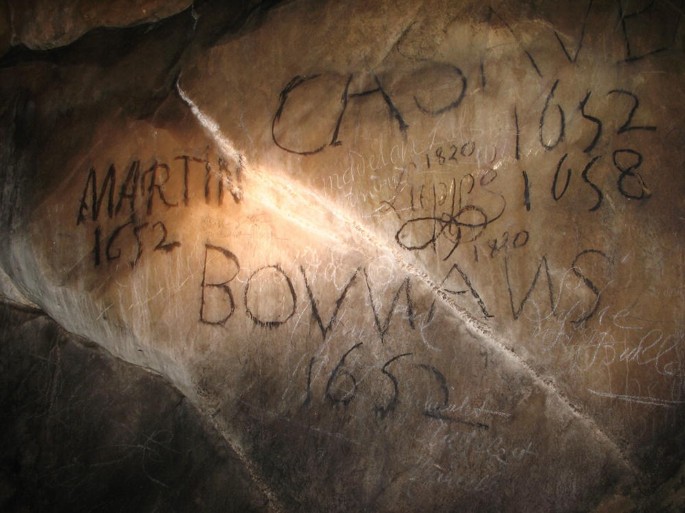 A photograph exhibits graffiti with text written on the rocks of the Niaux Cave.