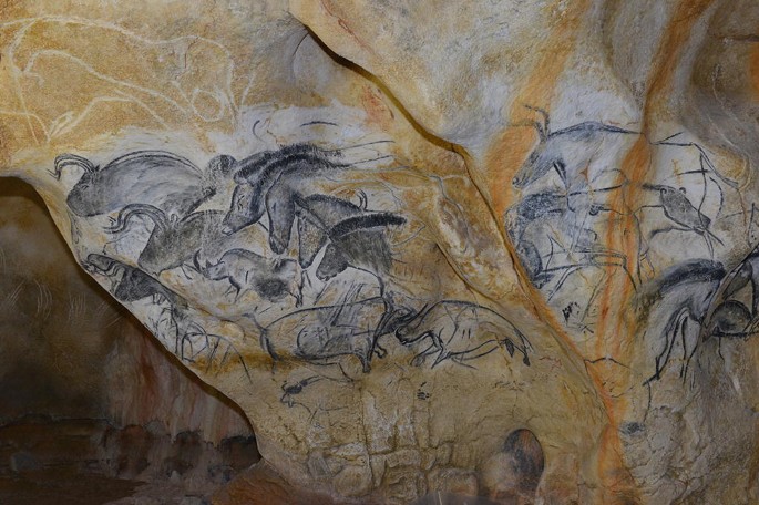 A photograph of the cave walls covered in ancient drawings and paintings, depicting various animals.