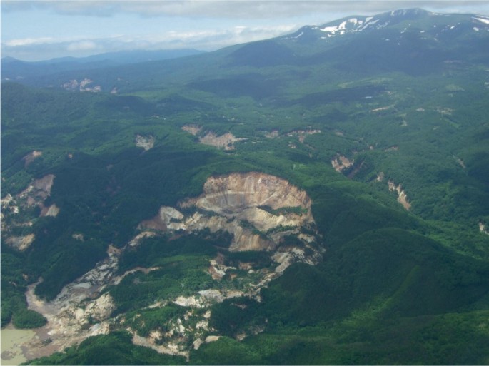 An aerial view of a large mass of land caved in at the top of a mountain.