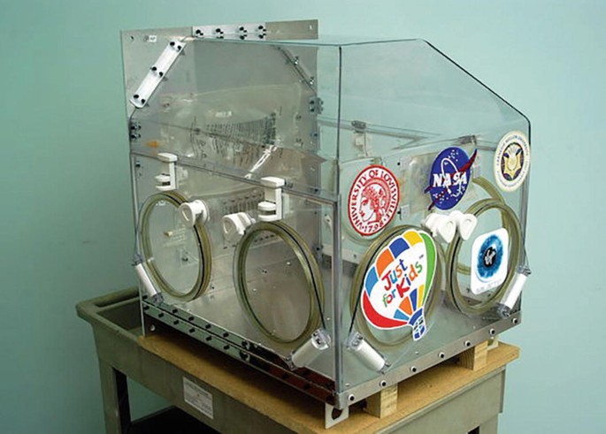 A photograph of a box made up of glass walls. The NASA logo, Just For Kid logo, University of Louisville logo, and Carnegie Mellon University logo are there on the box.