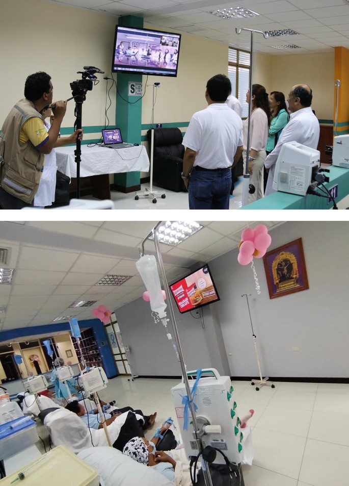 2 photos. Top, 4 people watching a television screen fixed in the wall which displays a hospital room setup. The screen is connected to a laptop and a man is capturing the screen in a camera. Bottom, a hospital room with patients sitting in chairs watching the television. Drip stands are near them.