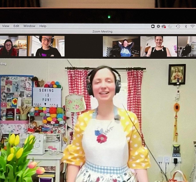A photograph of a computer screen with a woman presenting a video conferencing session with a group of online listeners.