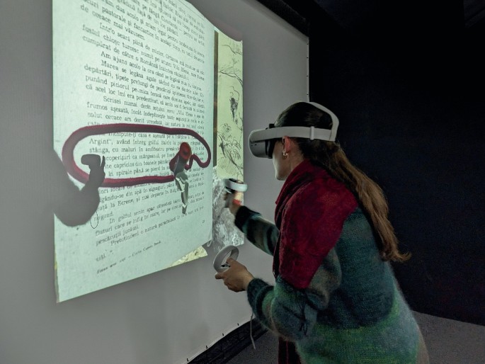 A screenshot of a V R room with darkened walls and a screen that has a projection of a page with text. A person wears a V R headset and holds a controller in front of the screen, thus encircling a portion of the text on the page with a virtual pencil.
