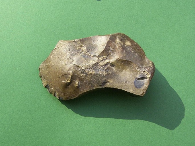 The front and backside photographs of an uneven stone hand axe placed over a flat surface.