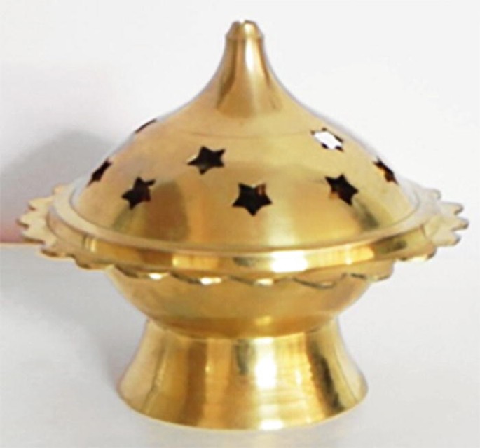A photograph of an incense burner has a cylindrical bottom and circular top with some star-shaped holes.