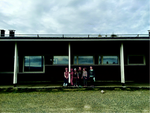 A picture of a group of students standing beside a building.