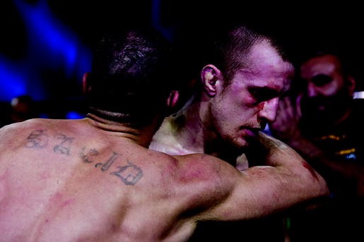 A photograph of two mixed martial arts fighters in Octagon embracing each other.