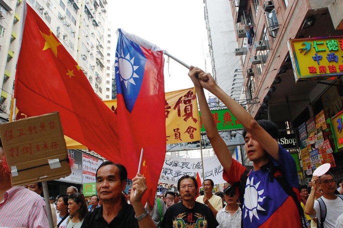 A photo of a group of people who protest on a street with Taiwanese and Hong Kong flags in their hands.