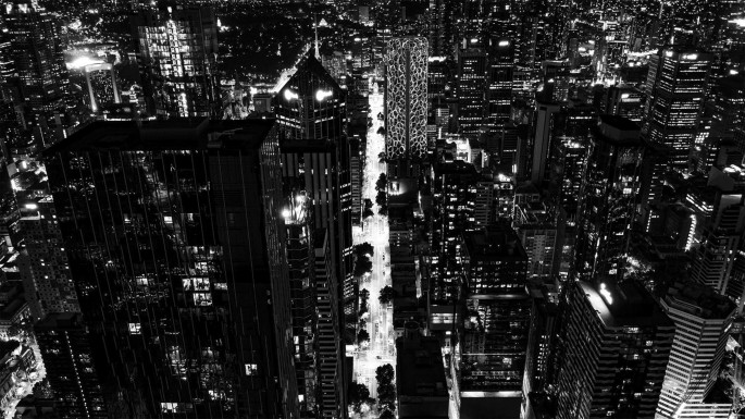 An aerial view photograph. It features skyscrapers and high-rise buildings in a city during nighttime.