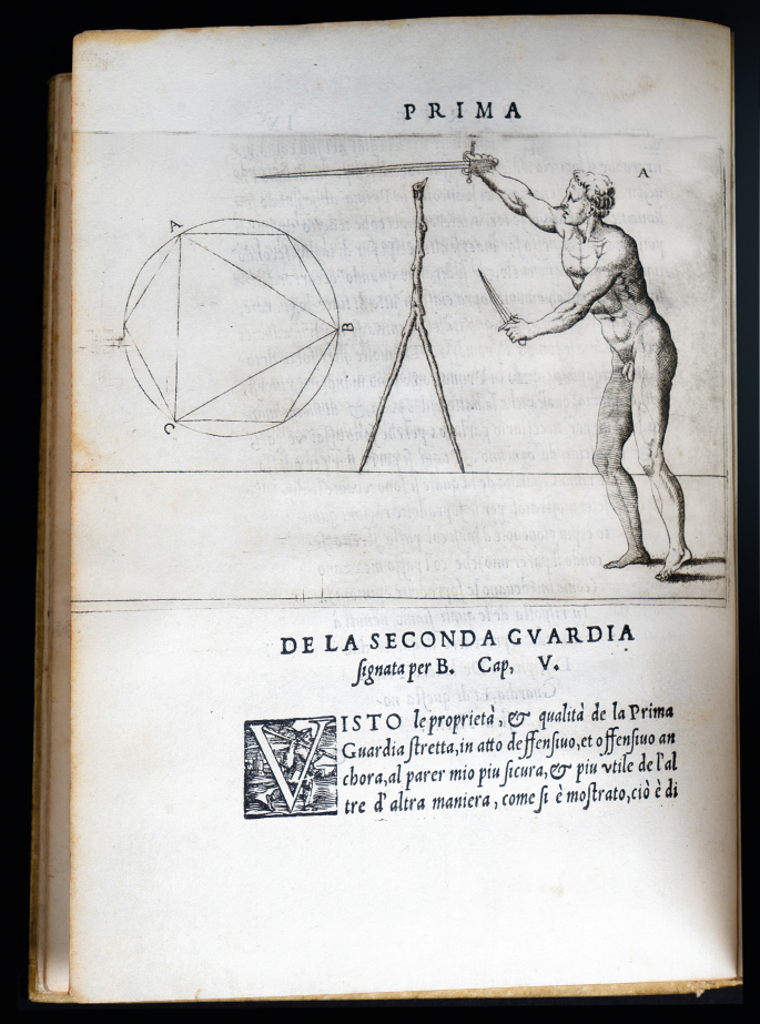 An old page with a sketch of P R I M A., a hexagon, and a triangle in a circle on the left, a wooden compass in the middle, and a naked man with two swords on the right. The bottom reads dela seconda gvardia and has a paragraph written below it.
