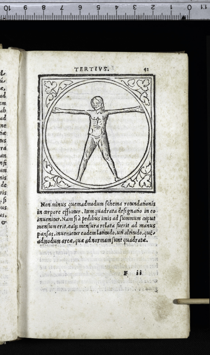 A page of an old book with a figure on the top and writings at the bottom. The figure has a naked man standing with arms stretched out horizontally inside a circle. The circle is bordered by a square with floral designs in the corners. The figure is labeled TERTIVS at the top. A scale is placed at the top of the book.