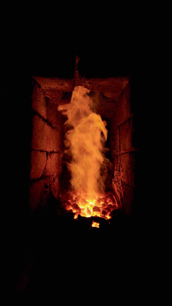 A photograph represents the burning of charcoal inside the furnace during construction.