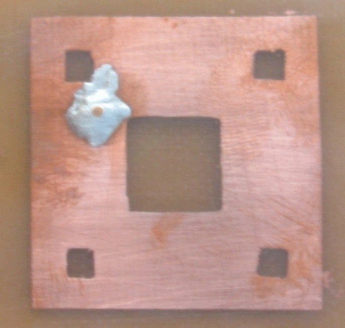 A close-up view of a fabricated antenna. It resembles a square with a square cutout in the middle and four smaller square cutouts in each corner.